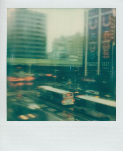 polaroid: buses blurred through a rainy green intersection, seen from above