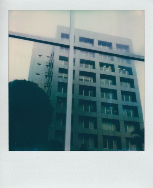 polaroid: an office tower seen through a rain-streaked window grid