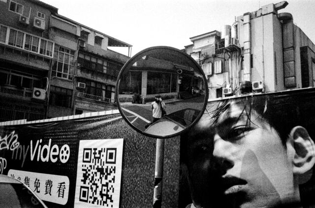 convex traffic mirror holding the photographer, billboard face watching from the right