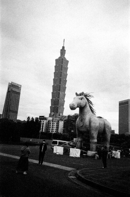 a giant inflatable unicorn facing taipei 101 across a parking lot